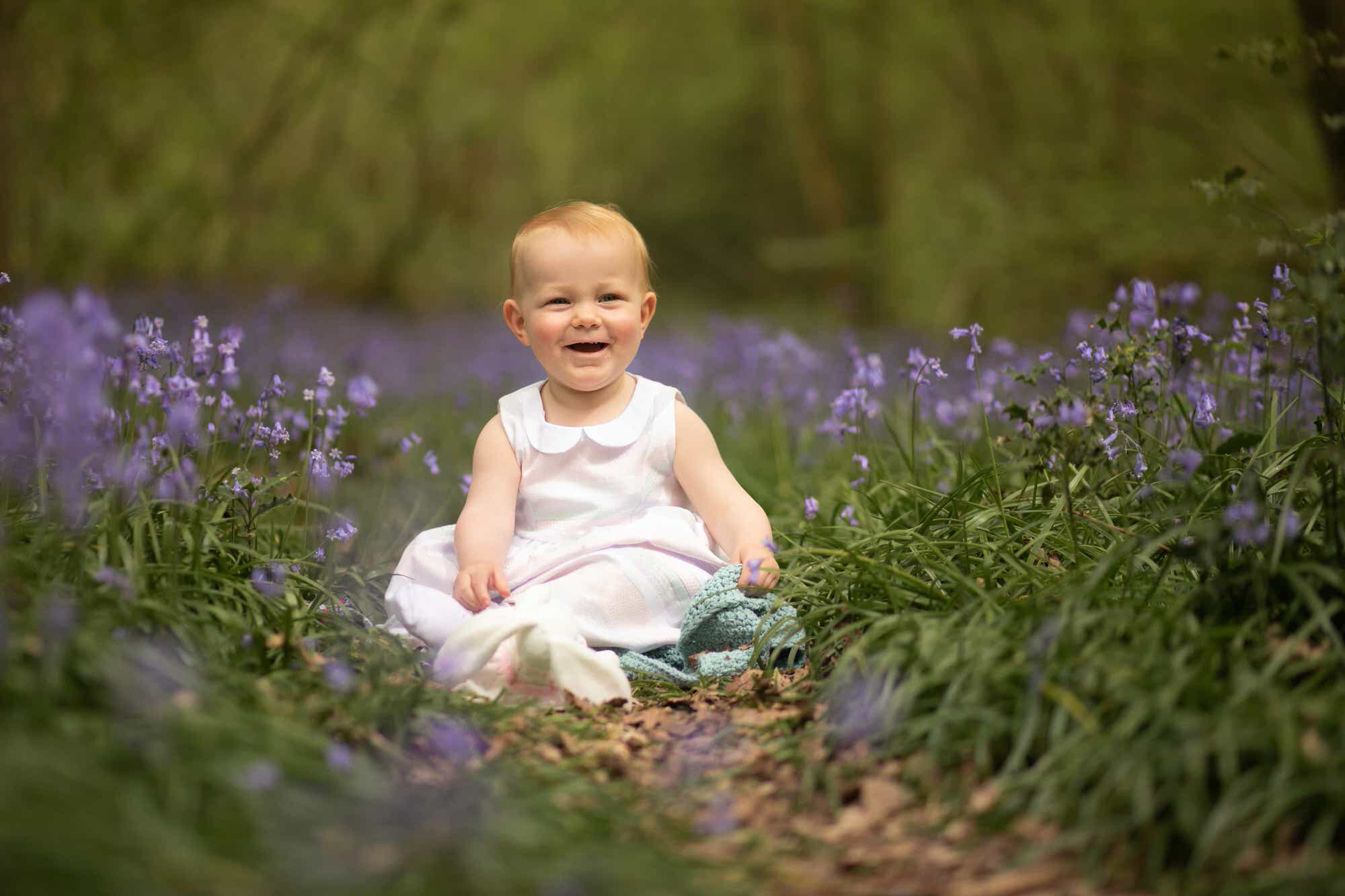 Smiling toddler in bluebells with teddy Bluebell photoshoot in Sussex family photographer Glasgow