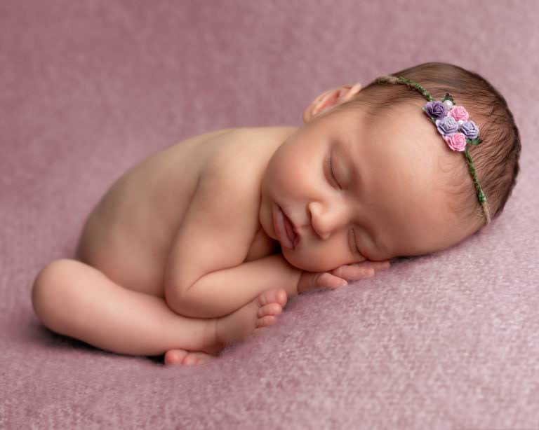 Glasgow newborn photography session with baby girl on mauve blanket, posed on tummy sleeping, wearing a dainty pink halo