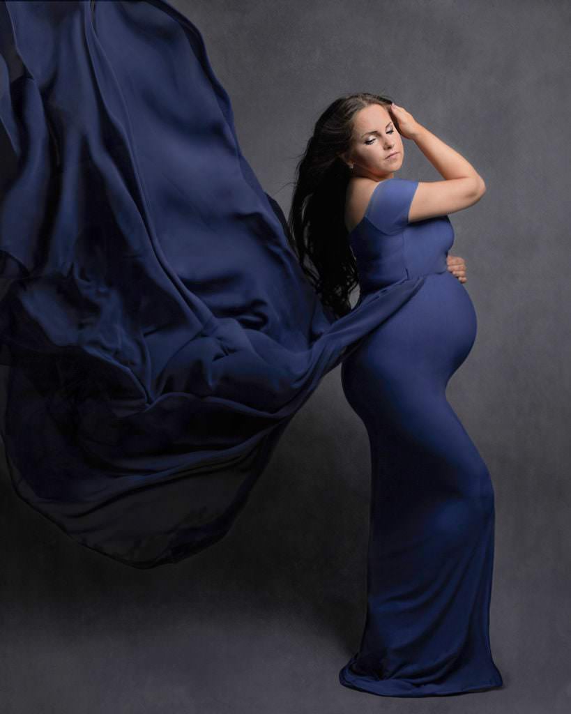 Glamorous shot of pregnant lady wearing blue maternity gown during pregnancy photoshoot