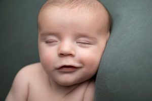 10 week old babe on blue sleeping & smiling. Part of a gallery from newborn photography shoot in Glasgow