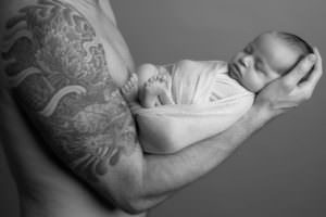 Black and white image of dad holding baby in his arm taken at newborn baby photoshoot in Glasgow