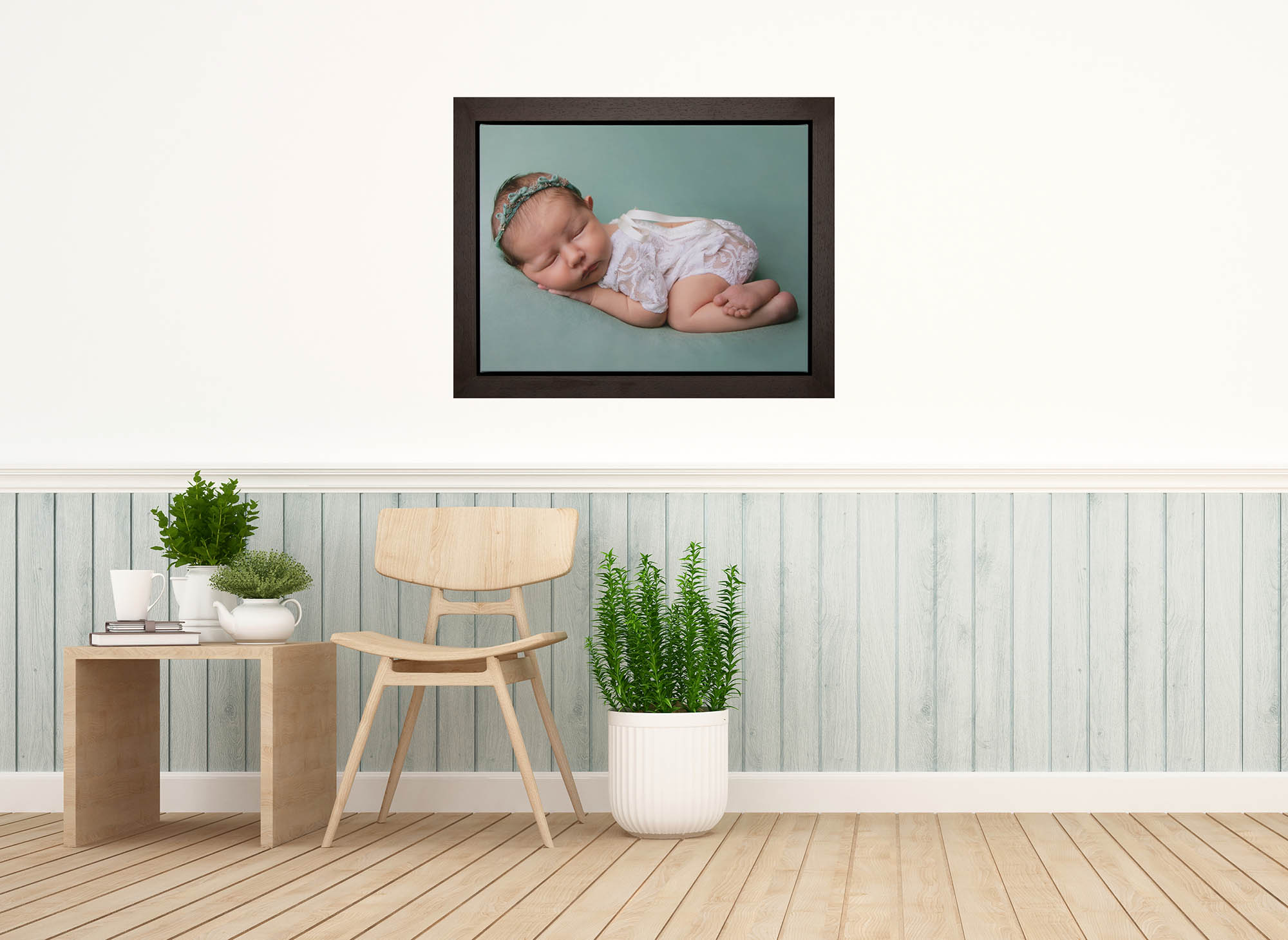Framed canvas of a baby girl on a green blanket, shown on the wall in a dining area. Image provided to show wall art available following a newborn photoshoot by Glasgow photographer