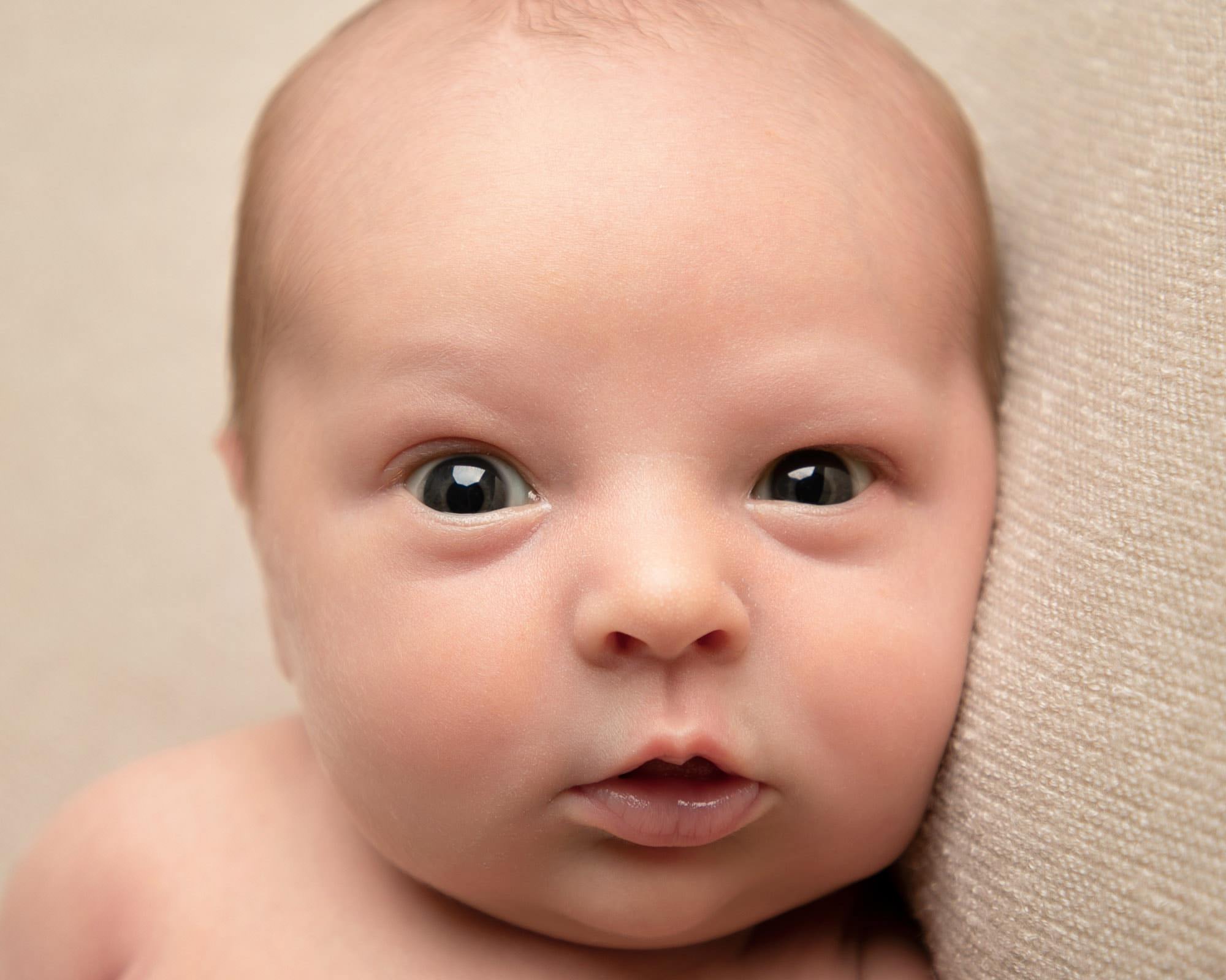 Baby boy eyes open looking at camera during newborn photoshoot by Glasgow baby photoshoot