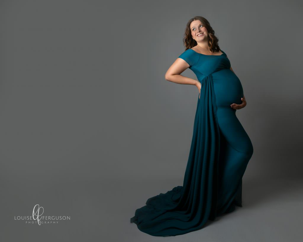 Pregnant female in green gown grey backdrop in Photoshoot