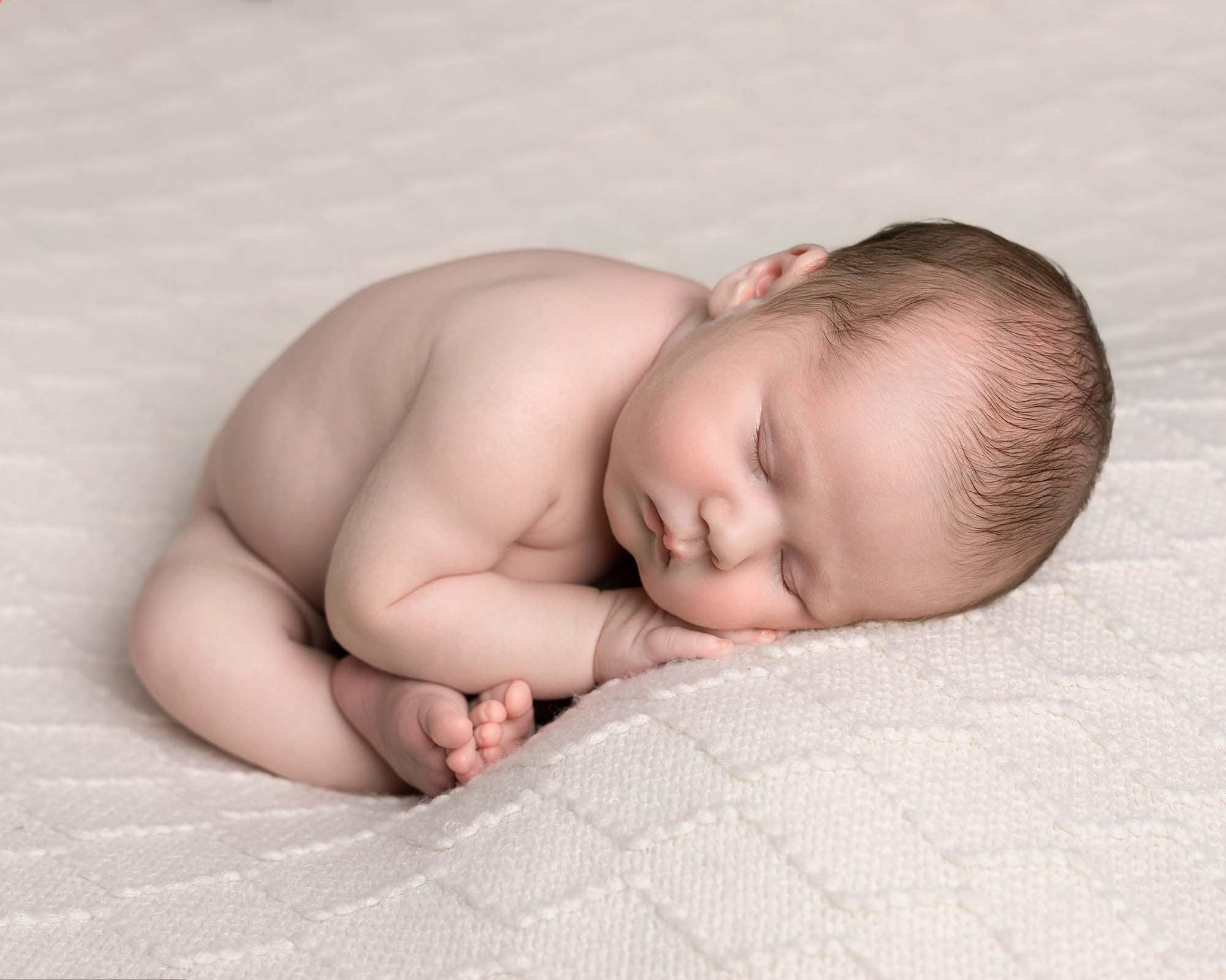Newborn Photographer in Glasgow image of baby boy in taco pose on cream blanket whilst sleeping. Image taken at Newborn Mini Photoshoot