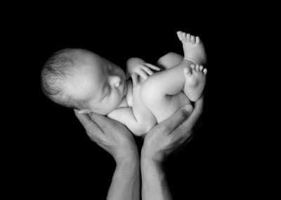 Black & white image of baby boy being held up in Daddy's hands. Image taken at Newborn Baby photoshoot Glasgow