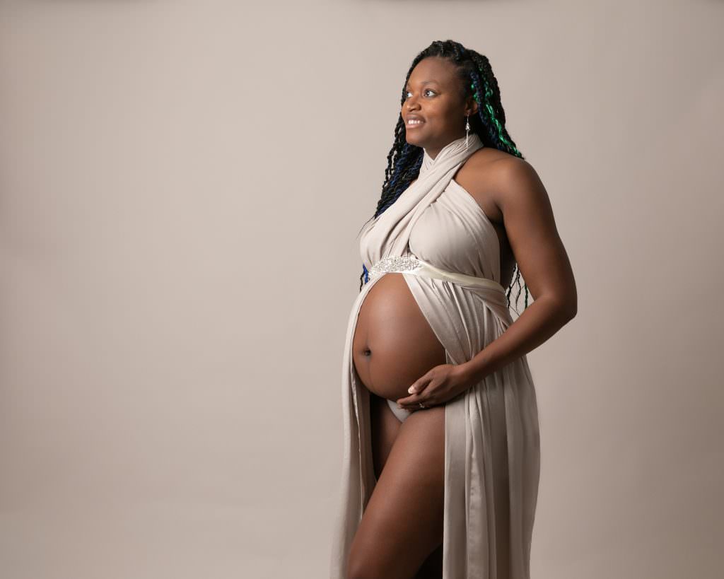 Naked pregnant female with cream silk shawl around her body on a dream backdrop.Image taken by Glasgow Maternity Photographer