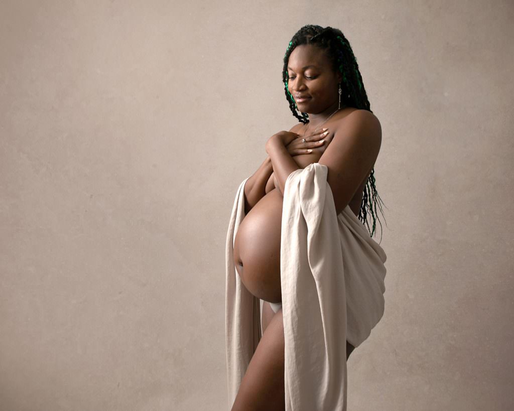 Naked pregnant female with cream silk shawl around her body on a dream backdrop.Image taken by Glasgow Maternity Photographer